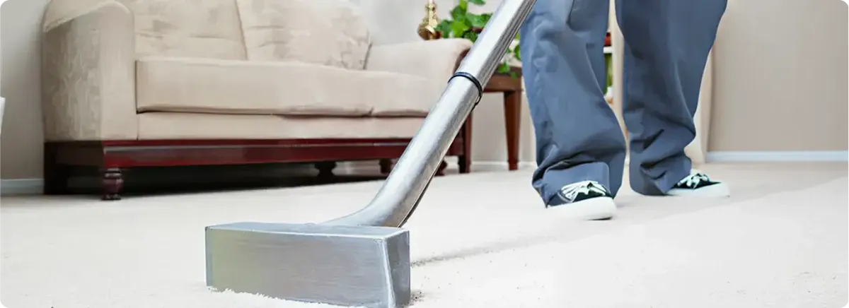 Carpet cleaning technician using a hot-water extraction wand on a light-colored carpet in a living room, Rockford, IL.